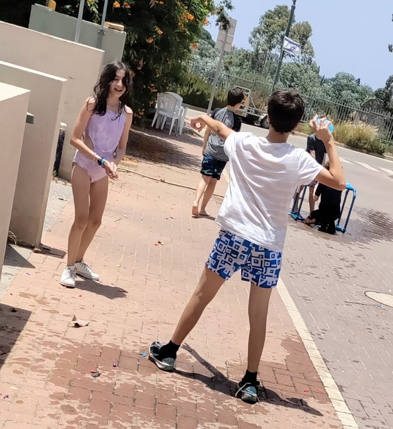 מלחמת בלונים ילד זורק בלון מים על ילדה